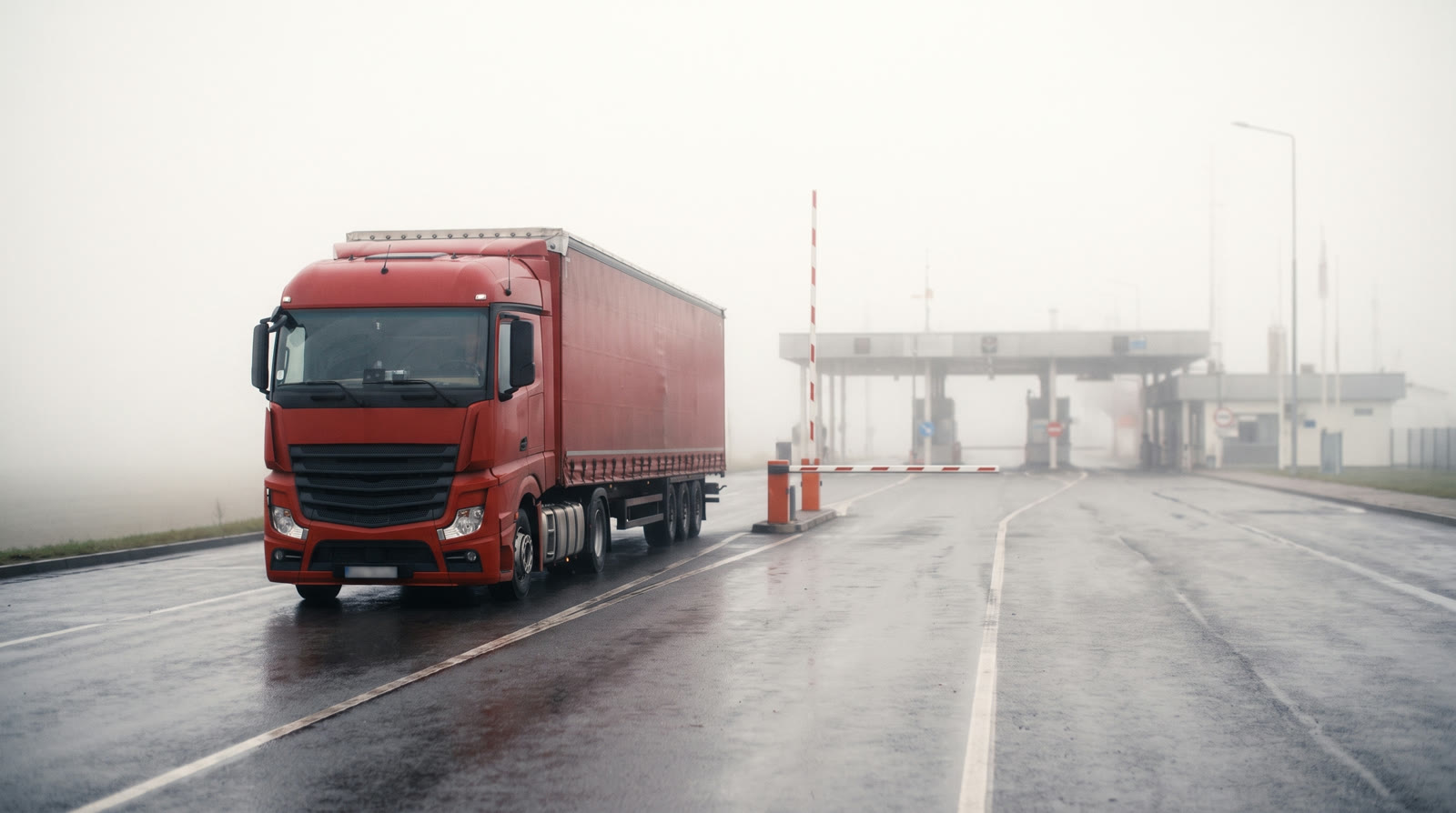 Ein roter LKW nähert sich auf nebliger Straße dem Zolltor, an der Schranke wartet ein Beamter in roter Warnweste